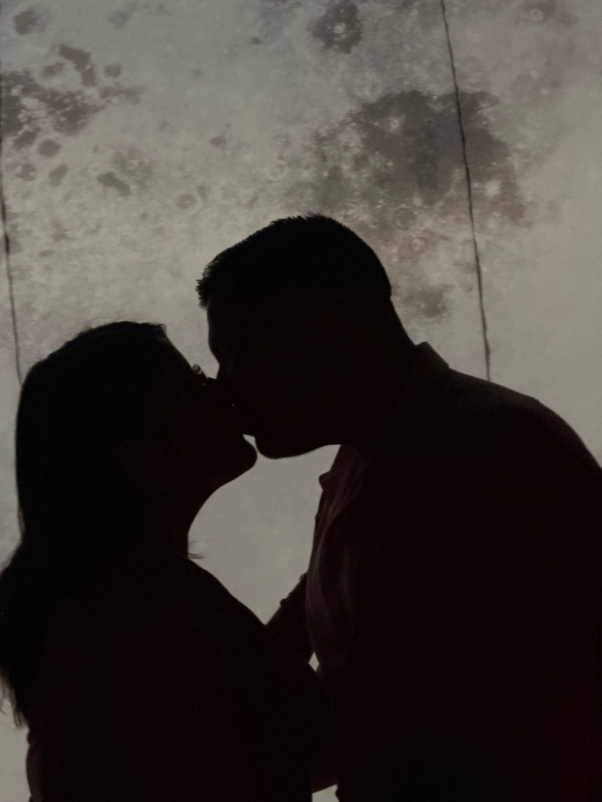 Una pareja comparte un beso frente a la luna