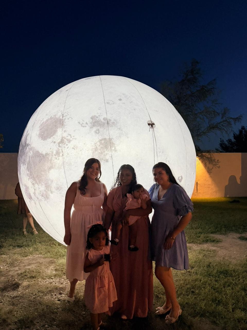 Invitadas y niñas posando junto a la luna iluminada